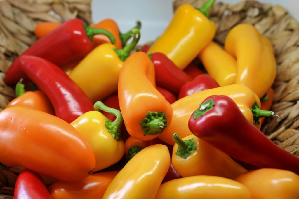 Colorful bell peppers in a woven basket, showcasing fresh produce for culinary and health inspiration.